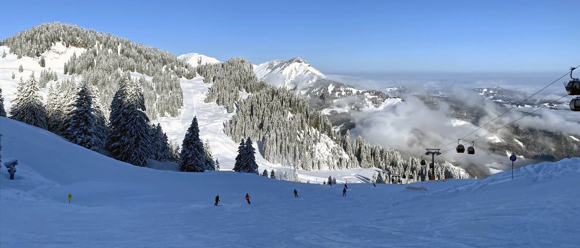 Sports weeks in our fitness hotel Snow-covered mountains with skiers and chairlift under clear blue sky