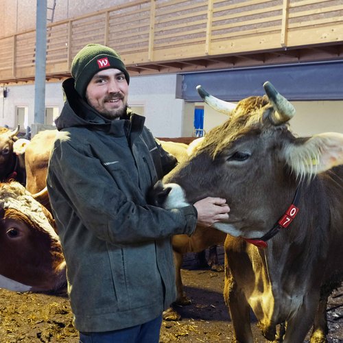 Wissen, das inspiriert: Unsere Vortragsreihe greift Themen auf, die das Leben bereichern. Bauer streichelt Kuh in einem Stall mit mehreren anderen Kühen