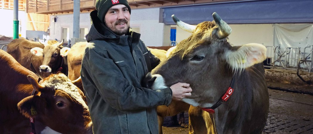 Wissen, das inspiriert: Unsere Vortragsreihe greift Themen auf, die das Leben bereichern. Bauer streichelt Kuh in einem Stall mit mehreren anderen Kühen