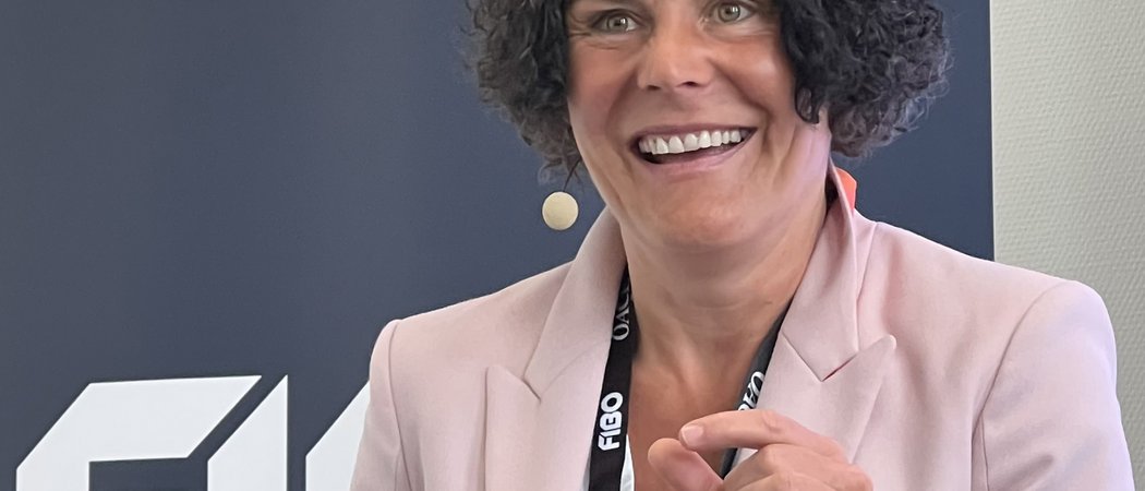 Wissen, das inspiriert: Unsere Vortragsreihe greift Themen auf, die das Leben bereichern. Frau in rosa Blazer spricht vor FIBO-Logo und macht Handgeste