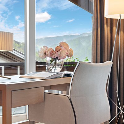Ihr Hotel in Oberstaufen: Allgäu Sonne Schreibtisch mit Stuhl vor Fenster mit Bergblick und Vase mit Blumen