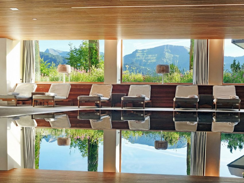 Ihr Hotel in Oberstaufen: Allgäu Sonne Innenpool mit Liegestühlen und Bergblick durch große Fenster