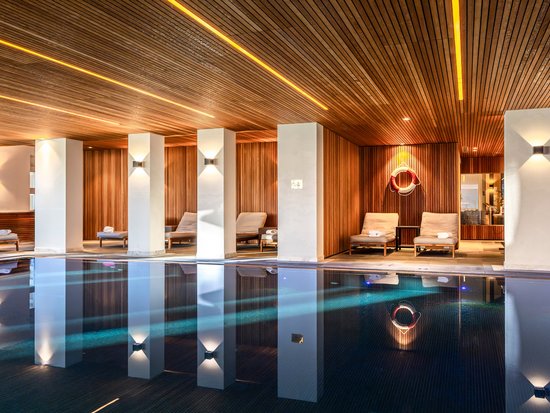 Hotel mit Pool im Allgäu: Allgäu Sonne Beheizter Innenpool mit Holzdecke und Liegestühlen in einem stilvollen Wellnessbereich