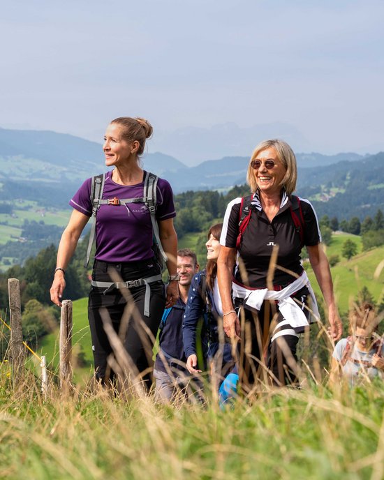 Ihr Wellnesshotel im Allgäu Gruppe von Menschen wandert auf einem Grasweg in einer bergigen Landschaft