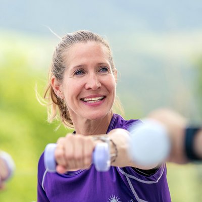 Das Breathwork Retreat Lächelnde Frau trainiert mit leichten Hanteln im Freien