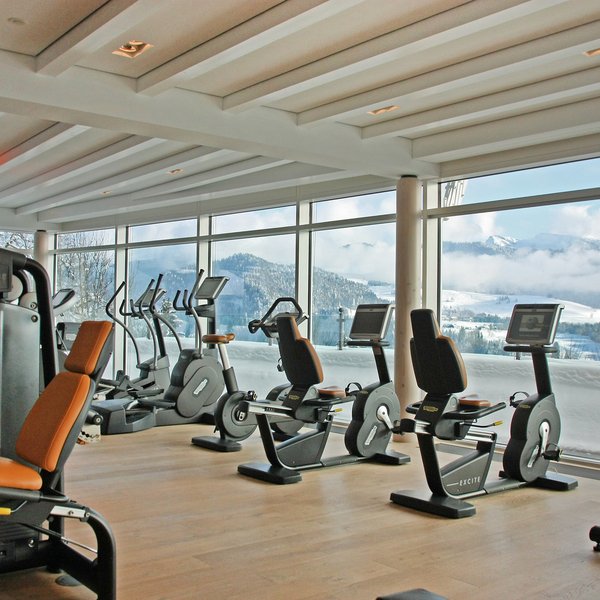 Ihr Wellnesshotel im Allgäu Fitnessraum mit Aussicht auf schneebedeckte Berge durch große Fenster