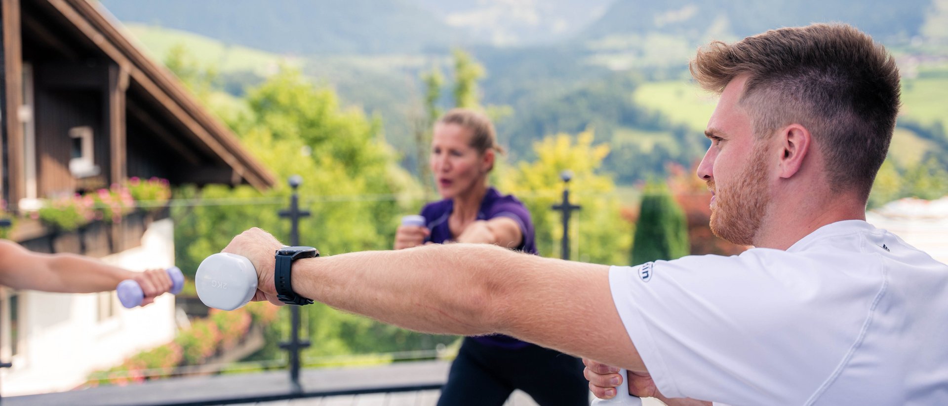 Your sports hotel in Allgäu: Allgäu Sonne Group exercising with dumbbells on terrace with mountain view