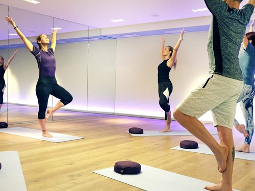 Sportwochen in unserem Fitnesshotel Yoga-Kurs mit Frauen und Mann, die Baum-Pose in einem Studio ausführen