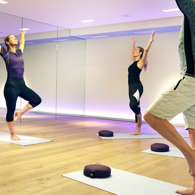 Sportwochen in unserem Fitnesshotel Yoga-Kurs mit Frauen und Mann, die Baum-Pose in einem Studio ausführen