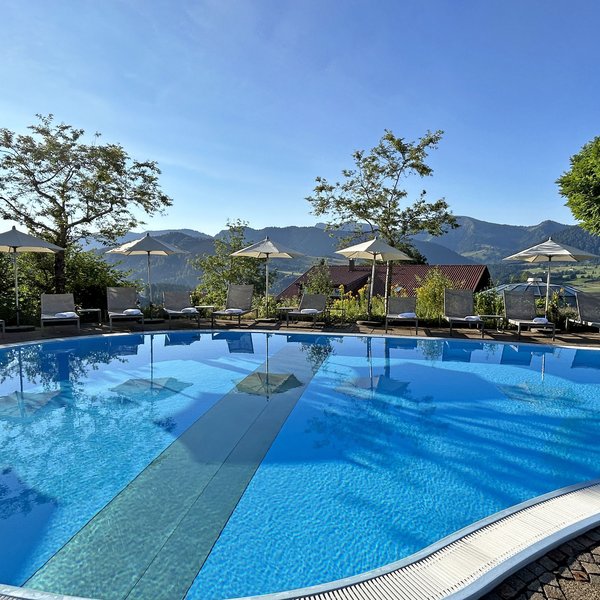 Oberstaufen: Hotel Allgäu Sonne Empty pool with umbrellas and lounge chairs against mountain landscape