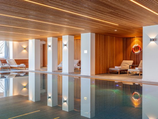 Hotel mit Pool im Allgäu: Allgäu Sonne Innenraum eines modernen Hallenbads mit Liegestühlen und Holzverkleidung