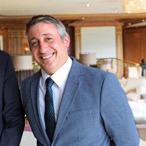 Our mission: your dream holiday in Oberstaufen Man in suit smiling in an elegant indoor setting