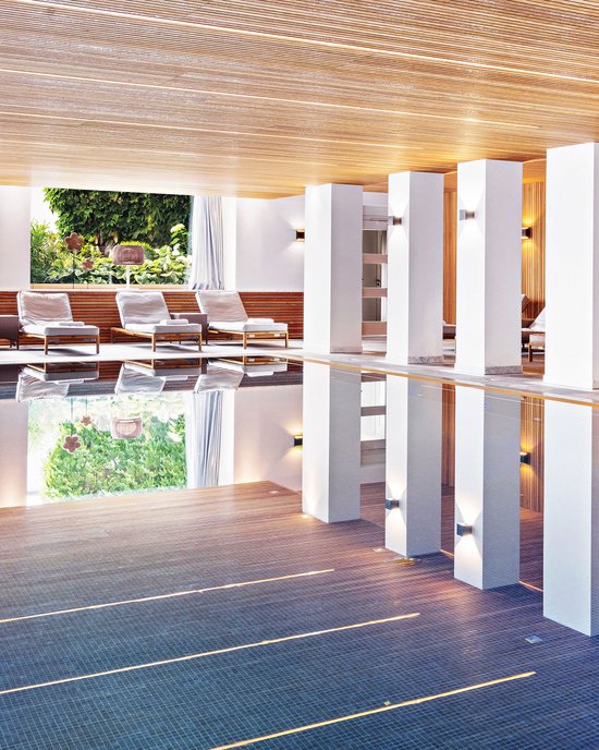 Oberstaufen: Hotel Allgäu Sonne Indoor pool area with lounge chairs and large windows showing outdoor greenery