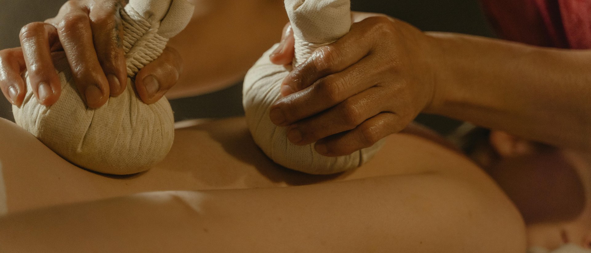 Allgäu Sonne – Ihr Ayurveda-Hotel im Allgäu Massage mit Kräuterstempeln auf dem Rücken einer liegenden Person