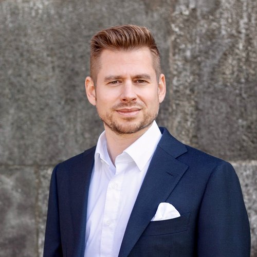 Wissen, das inspiriert: Unsere Vortragsreihe greift Themen auf, die das Leben bereichern. Porträt eines Mannes in blauem Anzug und weißem Hemd vor grauer Wand