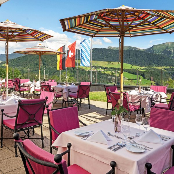 Oberstaufen: Hotel Allgäu Sonne Restaurant terrace with colorful umbrellas overlooking green hills