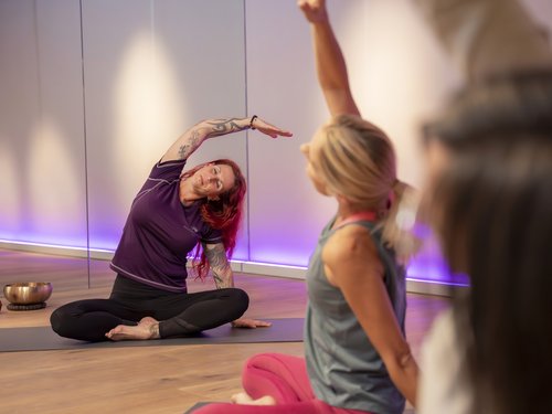 Sportwochen in unserem Fitnesshotel Yoga-Gruppe übt im Sitzen eine seitliche Dehnung im Kursraum