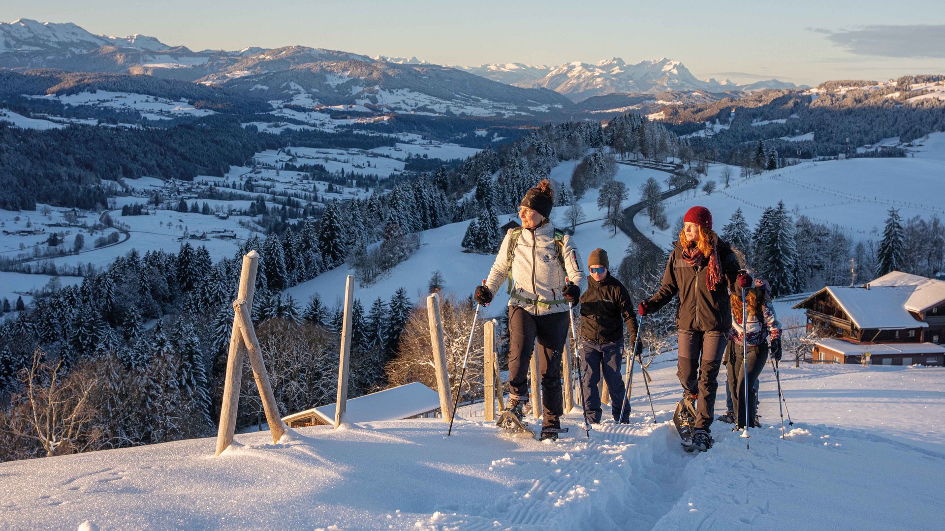 Ihr Wellnesshotel im Allgäu Gruppe beim Schneeschuhwandern in verschneiter Berglandschaft bei Sonnenuntergang